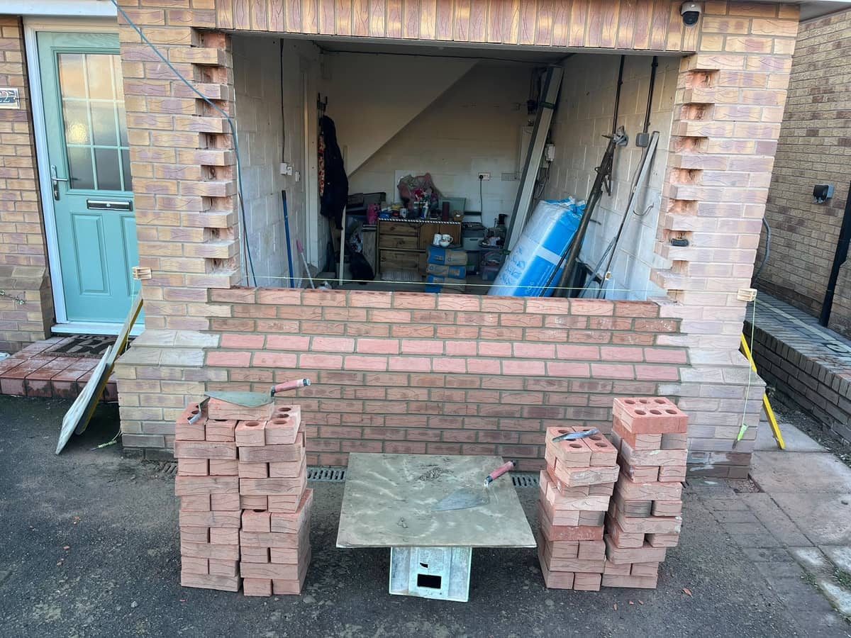 The garage front built up to sill height, bricks stacked either side