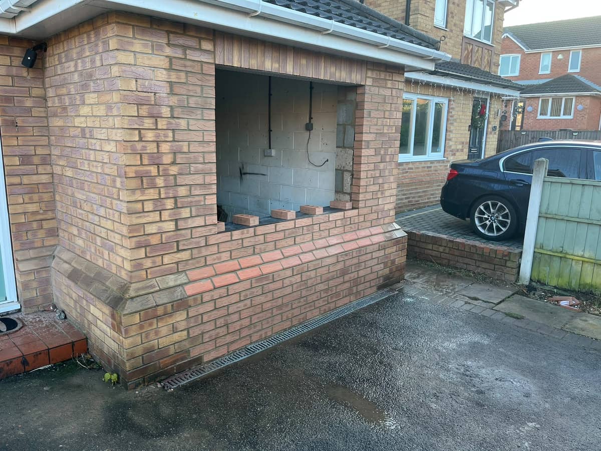 The converted garage front from the side, new brickwork around a wide window opening