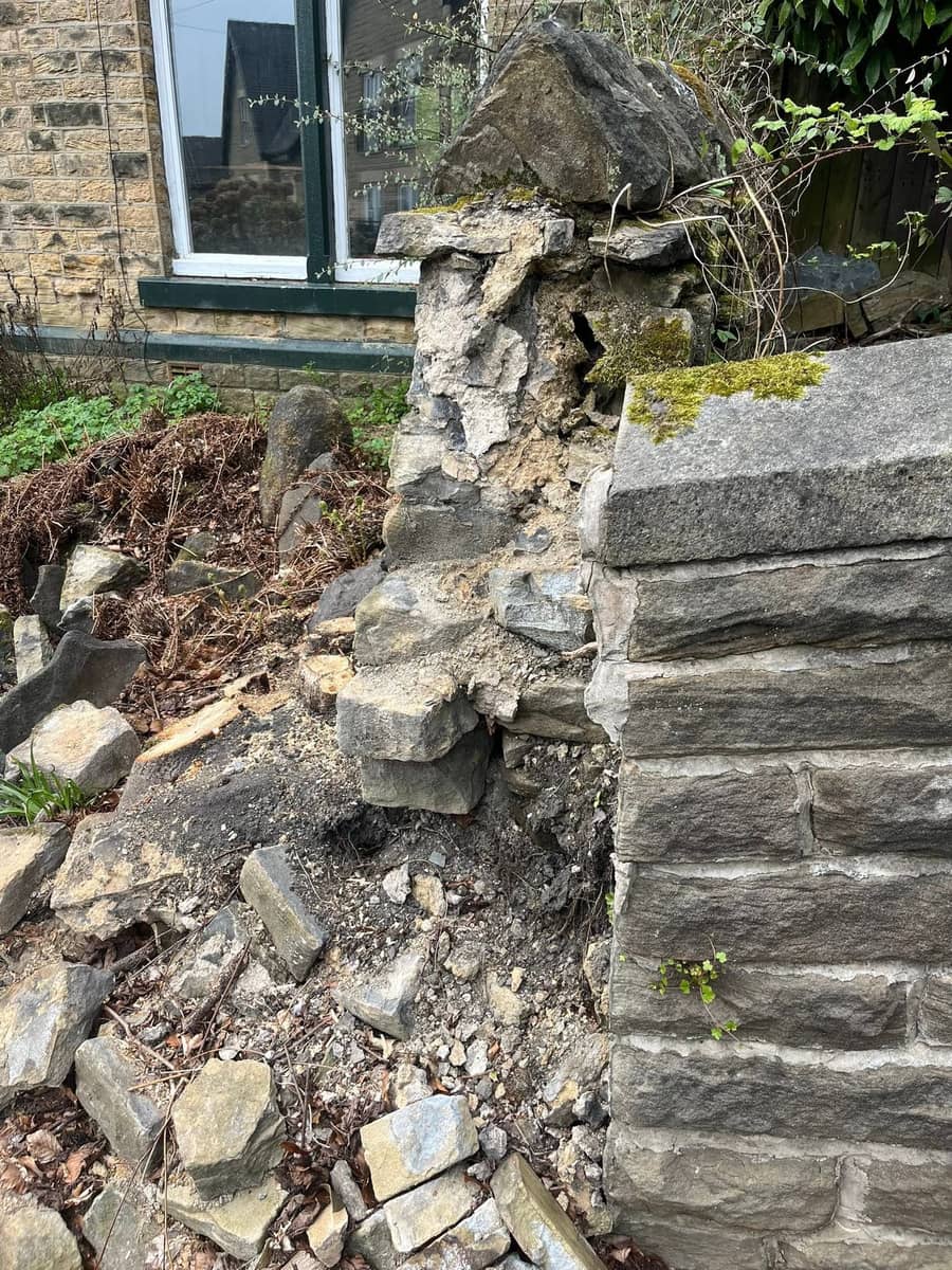 The broken end of the collapsed sandstone wall, loose stones and soil where the corner came down